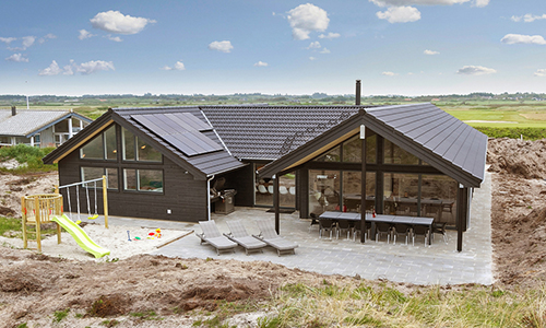 Blick auf ein schwarzes Gruppenferienhaus an der dänischen Nordseeküste